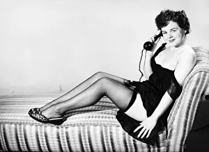 Clothing: Fashion: Stockings and garters. Model sitting in armchair with telephone