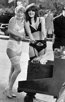 Clothing Underwear: Chilly models in lingerie warm up from a fire in a bin in the street