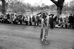 A clown stilt walker seen here riding a oversize bicycle in the Easter parade