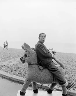 Suits And Jackets Prints: Comedian and actor Norman Wisdom photographed on Brighton Beach on a stuffed donkey