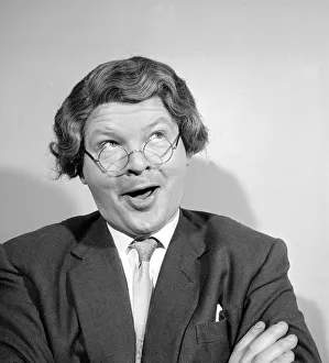Comedian Benny Hill pictured at home wearing a wig and glasses May 1958