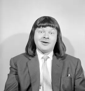 Comedian Benny Hill pictured at home wearing a wig May 1958