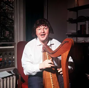 Harp Prints: The comic actor Benny Hill in his Kensington flat February 1966 playing a harp