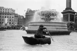 00967 Prints: Coracle fishermen in London. One of the fishermen paddles his coracle round Trafalgar