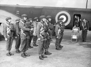 Parachute Prints: The corporal inspecting the parachute equipment of British parachutists before they enter