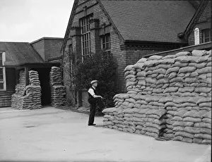 Warwickshire Prints: A council workman surveys the sandbag protection at an un-named school in the West