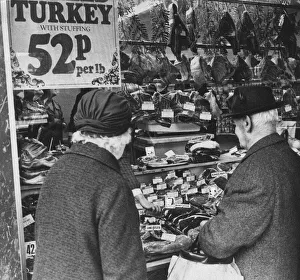 Couple looking at meat products on display in butchers shop, Cardiff, Wales