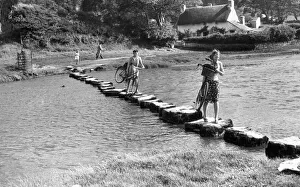 Carrying Prints: A couple of young women use stepping stones to cross the Ewenny River that rises to