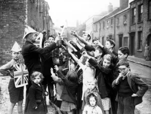 00114 Prints: Coventry children are given union jack paper hats and posters to help them celebrate VE