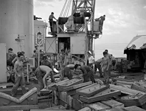 The crew of the County Class cruiser HMS London taking on board supplies