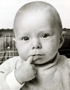 Thoughtful Prints: A cute baby looking bemused thinking with one finger in his mouth October 1969