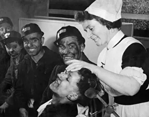 Care Prints: Cyril Annisworth, a 16 years old screen worker bites his lip as sister Ada swabs out his