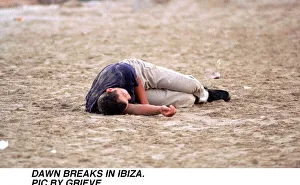 Dawn breaks in Ibiza Spain Drink Drunk youth Young man sleeps it off on the beach