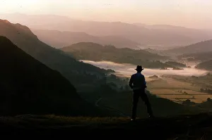 00134 Prints: Dawn rises over the Lake District as a walker travels along a lakeland pass