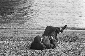 00948 Prints: A day-tripper from Londons East End, relaxes in the summer sunshine on the beach