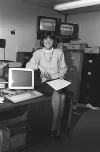 DEBBIE THROWER - TV PRESENTER SITTING ON A DESK WITH COMPUTER AND TV SCREENS - 05 / 01 / 1988