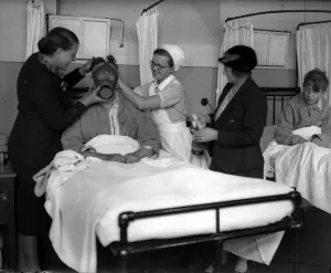01004 Prints: Demonstrating a gas mask on a patient in hospital in the early years of the Second World