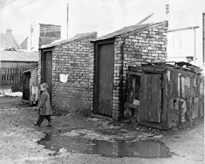 00054 Prints: Derelict housing in an area of North East - A young boy walks the flooded walkway to