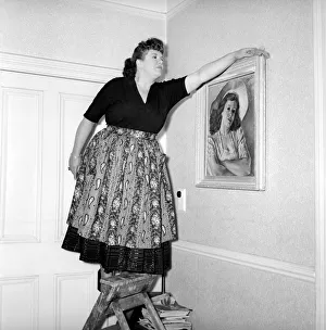 Dusting Prints: Domestic Life: Woman (Mrs. Olive Haugh) dusting the picture frame. Circa 1954