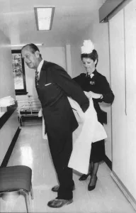 01440 Prints: The Duke of Edinburgh. Prince Philip being helped with his protective clothing by Matron