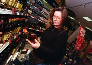 Spirits Prints: Duty free shop at Edinburgh airport February 1999 Woman looking at bottle of spirits