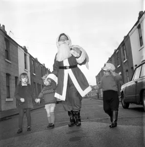 An elderly woman dressed as Santa Claus on her way to an engagement accompanied by