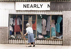Walking Stick Prints: An elderly woman pauses to look at the World War Two prefab shop on the corner of
