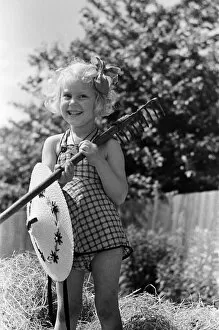 Girl Collection: Ella Edwards holding a rake and a sun hat. August 1941