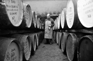 Workman Prints: An employee of the Knockando Whisky Distillery in Scotland checks the casks in