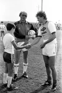 Umbro Prints: England captain Bryan Robson shakes hands with one of the boys of the local football club