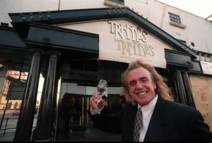 01181 Prints: English nightclub owner Peter Stringfellow posing with a glass of champagne outside