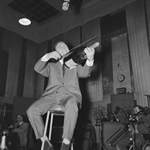English singer Matt Monro with a giant size bottle of champagne as he works on his latest