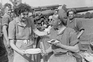ENSA girl Marjorie Jarvis compliments an artilleryman on his cooking at a base in France