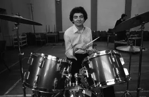 Entertainer Rowan Atkinson practices on drum kit 1980