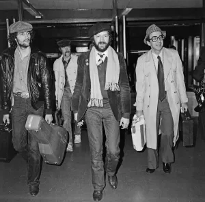 Eric Clapton (centre in beret) pictured leaving Heathrow airport for California