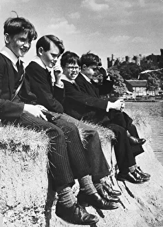 Private Prints: Eton pupils sitting on the edge of river bank of the Thames at Windsor. 1955
