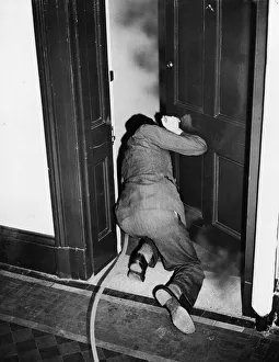 Bombs Prints: How to extinguish a fire bomb. A man crouches in the doorway of a smoke filled room
