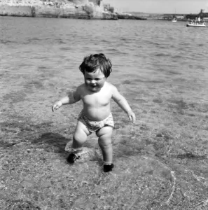 Sunshine Prints: Families on the beach at Plymouth: Baby girl having her first dip in the sea