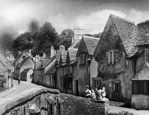 00266 Prints: A family takes a rest on a stone wall in a Cotswold village in Gloucestershire