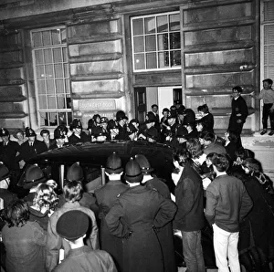 Fans of The Beatles watch as policemen escort group to their car