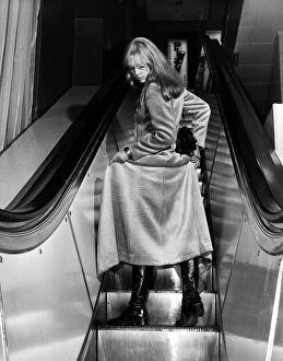 00196 Collection: Fashion Coats Maxi January 1970 Woman on an escalator holding up her coat to show