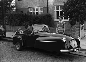 A father takes his son for a ride in his new convertible Bond mini car. Circa 1950