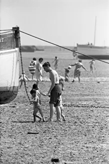 Holidaymaker Prints: A father with his young family seen here exploring the mud flats at Southend, Essex
