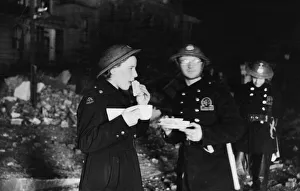 A female A. F. S. driver eating sandwiches by the light of a small fire during the Second