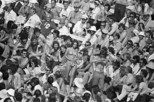 A female cricket fan in a bikini causes a stir as she walks through the crowd at Lord