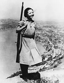 Female Guerilla fighter armed with weapon smiles for the camera during Second World War