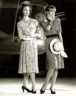 High Heels Prints: Two female models wearing 40s style evening dress with floral print holding a hat in one