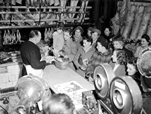 Sausages Prints: Film production company, filming a scene in a butchers shop as customers wait in long