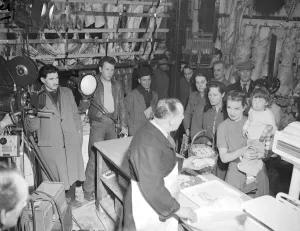 00100 Prints: Film production company, filming a scene in a butchers shop as customers wait in long