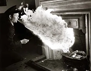 00151 Prints: fire eater - man blowing flames from mouth to light logs in fireplace